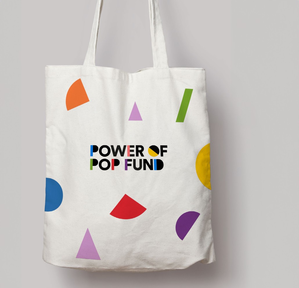 Image of tote bag with power of pop fund printed on it and colourful shapes.